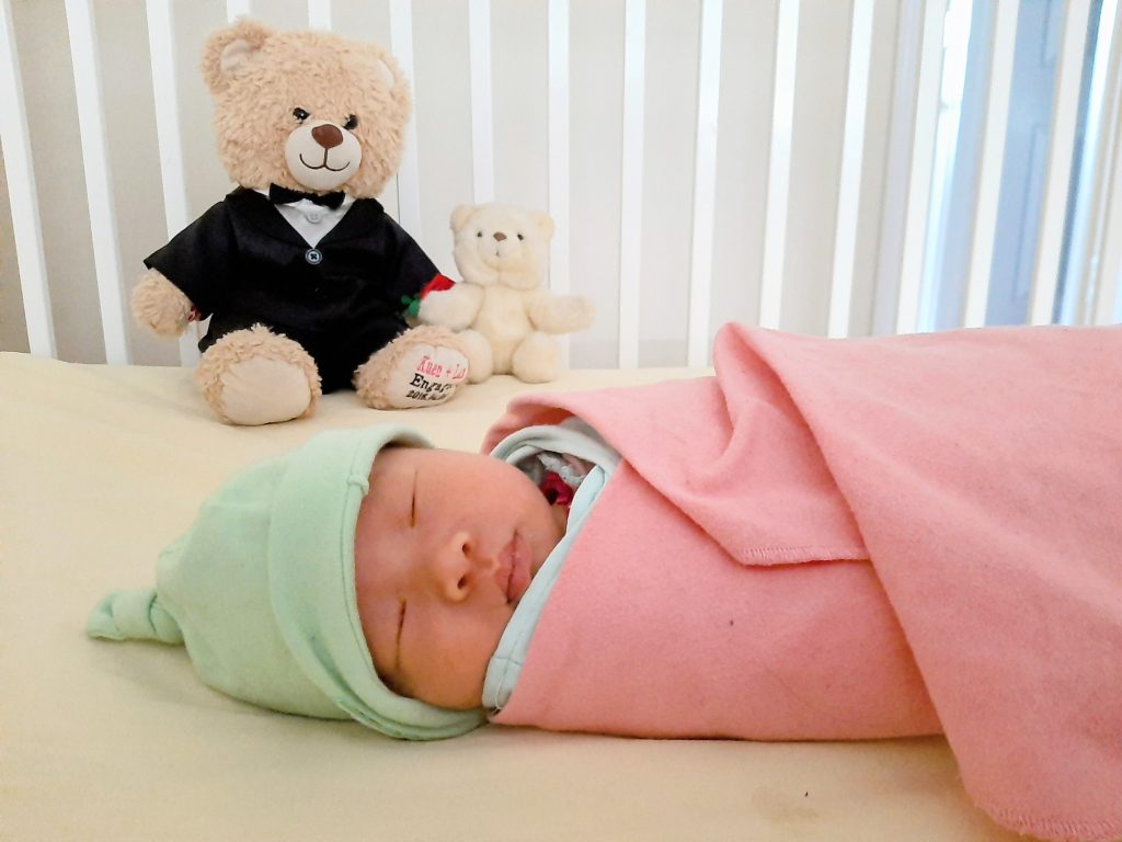 Newborn baby sleeping in crib in pink blanket